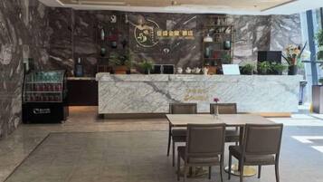 A hotel reception area with a marble counter, seating, and a display case.