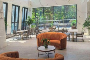 A spacious indoor area with a large window, a sofa, a round table, and several chairs. - Jiasheng Jinling Hotel (Nanjing)