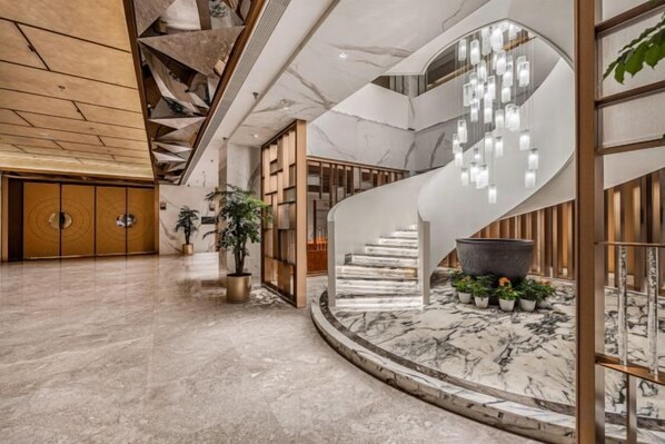 A spacious lobby with a marble floor, a curved staircase, and a modern chandelier. - Jiasheng Jinling Hotel (Nanjing)
