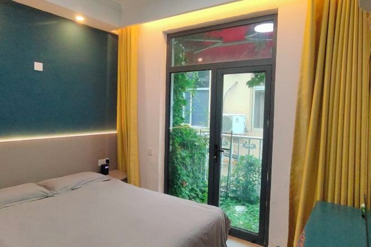 A hotel room with a bed, a sliding glass door to a balcony, and a nightstand.