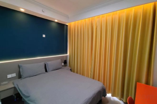 Una habitación de hotel con una cama, una mesita de noche y una cortina.