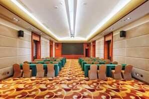 A conference room with rows of tables and chairs, a large screen at the front, and a patterned carpet. - Zhongxin Convention Center (Jinggangshan City)