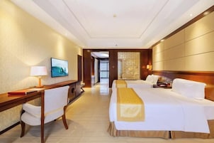 Habitación de hotel con cama, escritorio, silla y televisión.