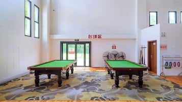 Amplio espacio interior con dos mesas de billar, alfombra estampada y una puerta que da a otra habitación.