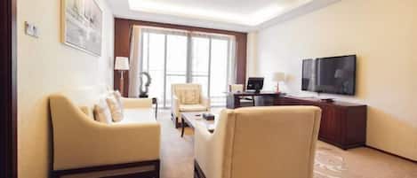 Une chambre d’hôtel équipée d’un canapé, d’un fauteuil, d’un bureau, d’une télévision et d’une grande fenêtre.