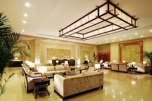 A spacious lobby with multiple seating areas, a high ceiling with a geometric light fixture, and traditional artwork on the walls. - Zhongxin Convention Center (Jinggangshan City)