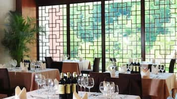 Un restaurante con mesas dispuestas para comer, con vista a través de una ventana de diseño geométrico.