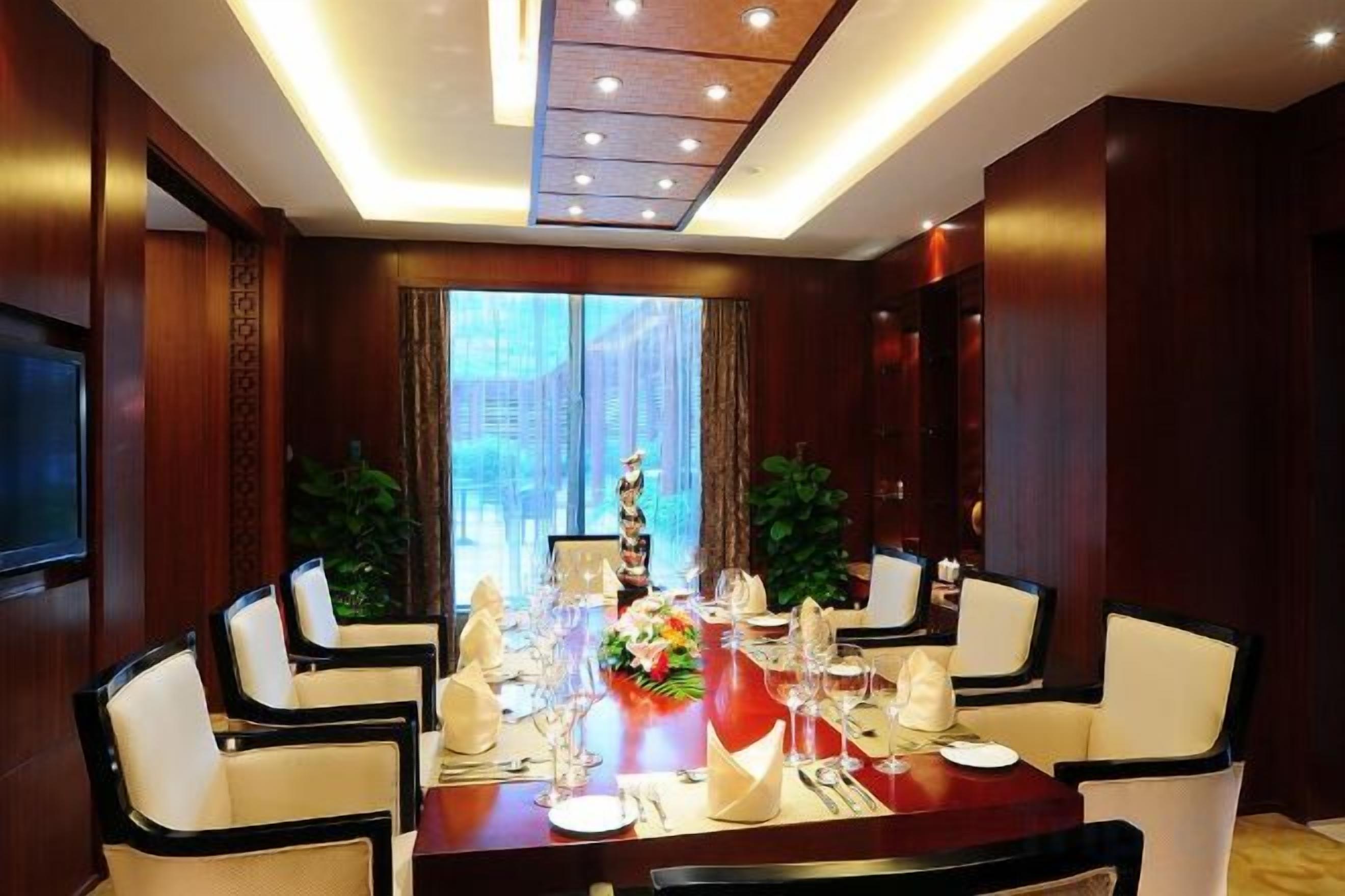 Un área de comedor con una mesa redonda, sillas y un televisor en la pared.
