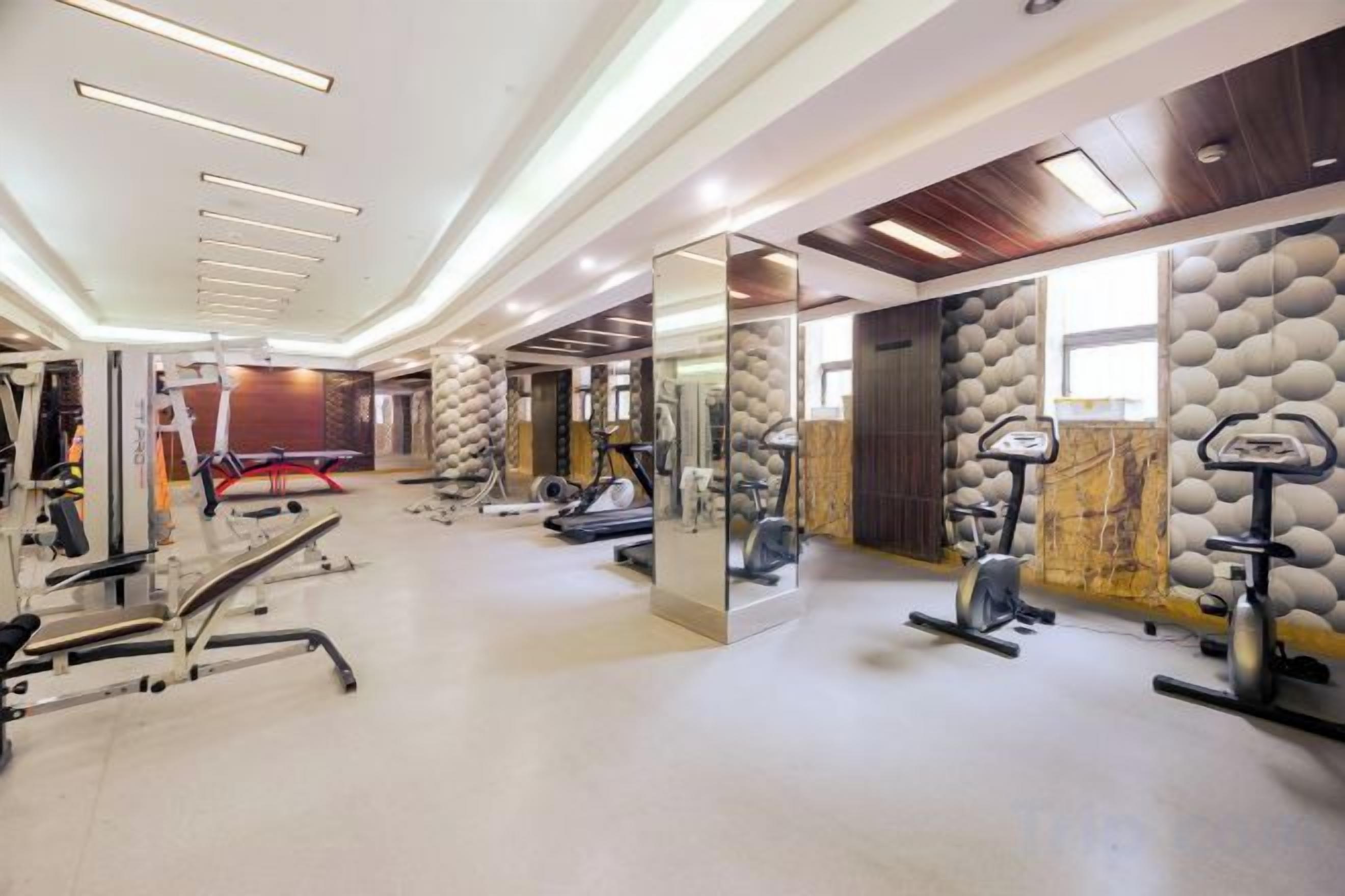 A gym with exercise equipment, a mirror, and a wall with a textured pattern.