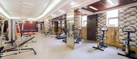 A gym with exercise equipment, a mirror, and a wall with a textured pattern.