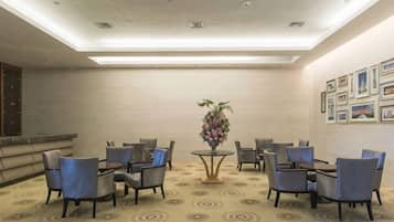 Un hall d’hôtel comprenant un comptoir d’accueil, un espace salon et une plante décorative.