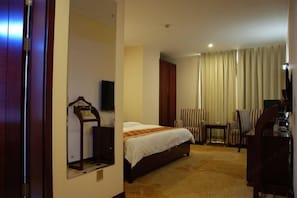 Una habitación de hotel con una cama, televisor, escritorio y una silla.