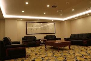 Un salón de conferencias con una pantalla grande, diversas opciones de asiento y una alfombra estampada.