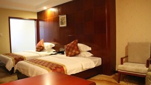 A hotel room with two beds, a wooden headboard, a desk, and a chair. - an Ran Hotel (Zhenkang)