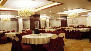 A banquet hall with round tables, red chairs, and chandeliers. - an Ran Hotel (Zhenkang)