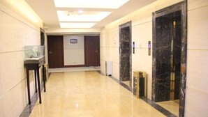 A hallway with a marble floor, a glass display case, and a marble elevator door. - an Ran Hotel (Zhenkang)