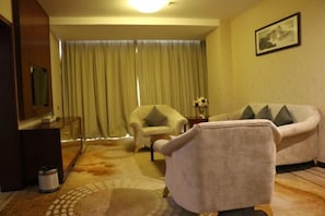Habitación de hotel con sofá, sillón y televisor.