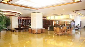 A spacious lobby with a polished floor, a reception area with a counter, and a seating area with chairs. - an Ran Hotel (Zhenkang)