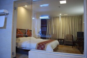 A hotel room with a bed, a chair, a television, and a window with curtains. - an Ran Hotel (Zhenkang)