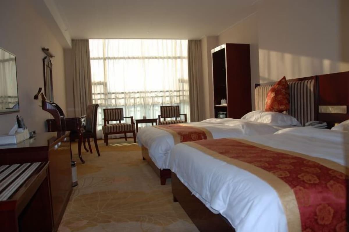 Habitación de hotel con dos camas, un escritorio, una silla y un piano.