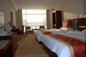 Habitación de hotel con dos camas, un escritorio, una silla y un piano.