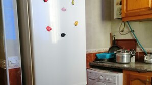Eine Küche mit einem weißen Kühlschrank, einer Waschmaschine und Holzschränken.