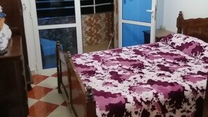 Ein Schlafzimmer mit Bett, Schrank, Kommode und einem Fenster mit Blick nach draußen.