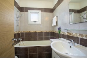 A bathroom with a bathtub, a sink, and a mirror. - Villa Marina in Pernera (Paralimni)