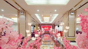 A hotel corridor with a central red sign, pink floral decorations, and a chandelier. - Tianbaolong Hotel (Fusui)