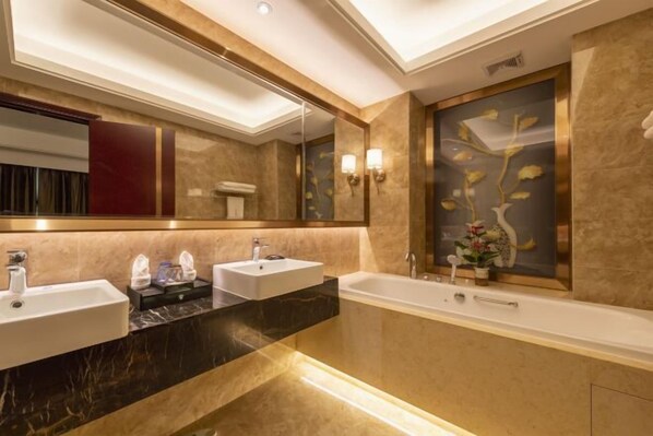 Une salle de bain moderne avec deux lavabos, une baignoire et un grand miroir.