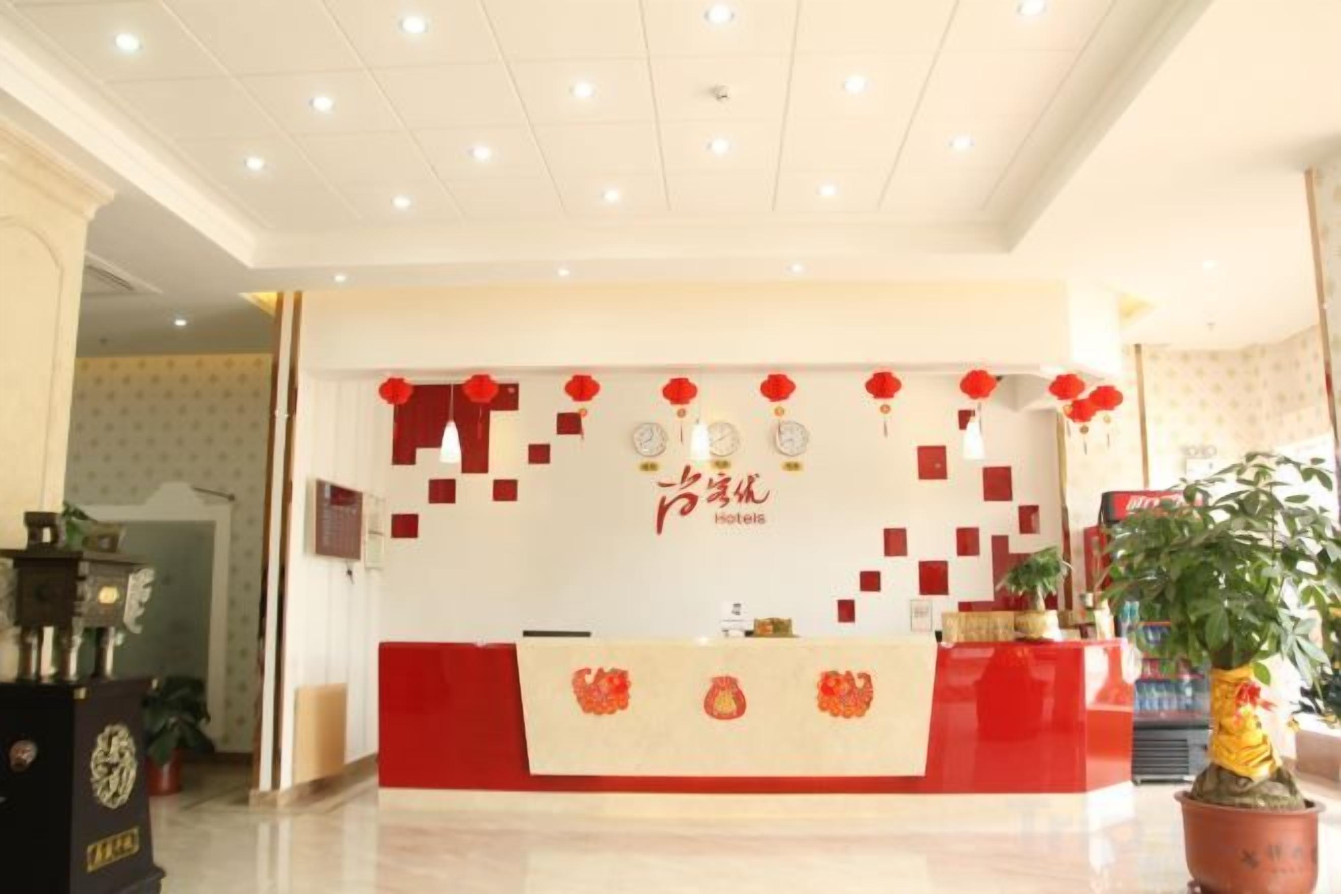 A hotel reception area with a red and white color scheme, a reception desk, and a potted plant.