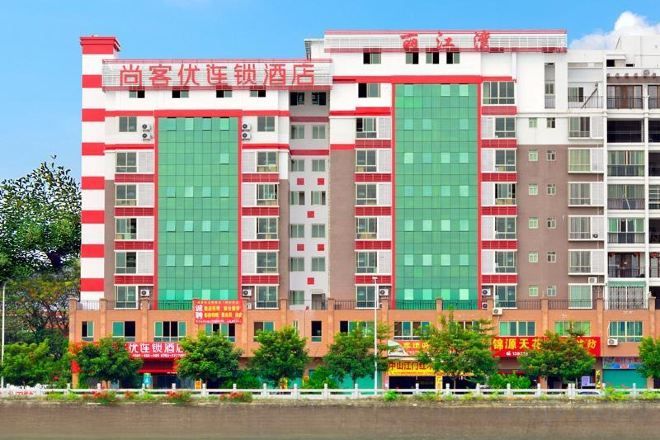 A multi-story hotel with a red and white facade, large windows, and a flat roof.