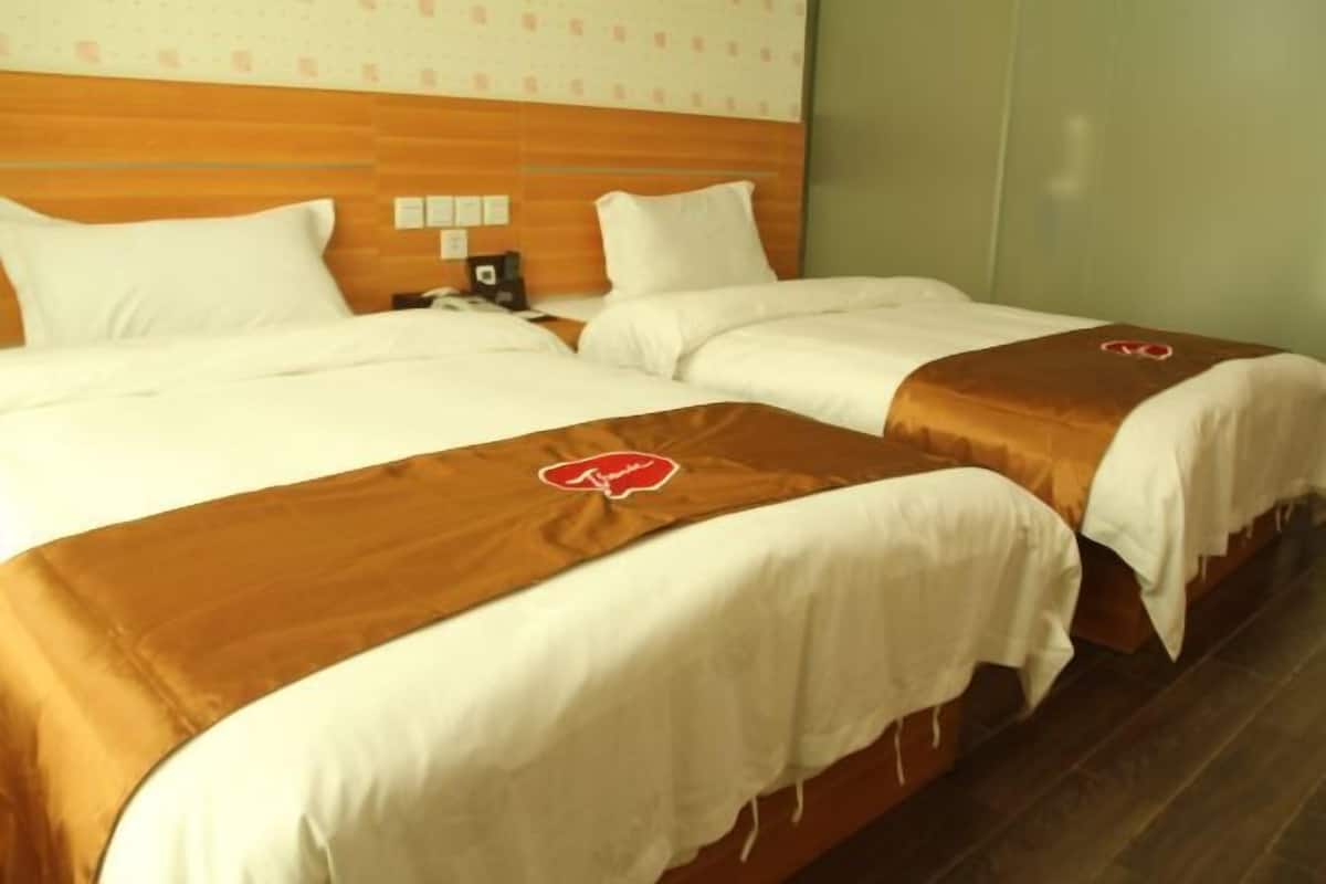 A hotel room with two beds, each with a brown headboard and white bedding.