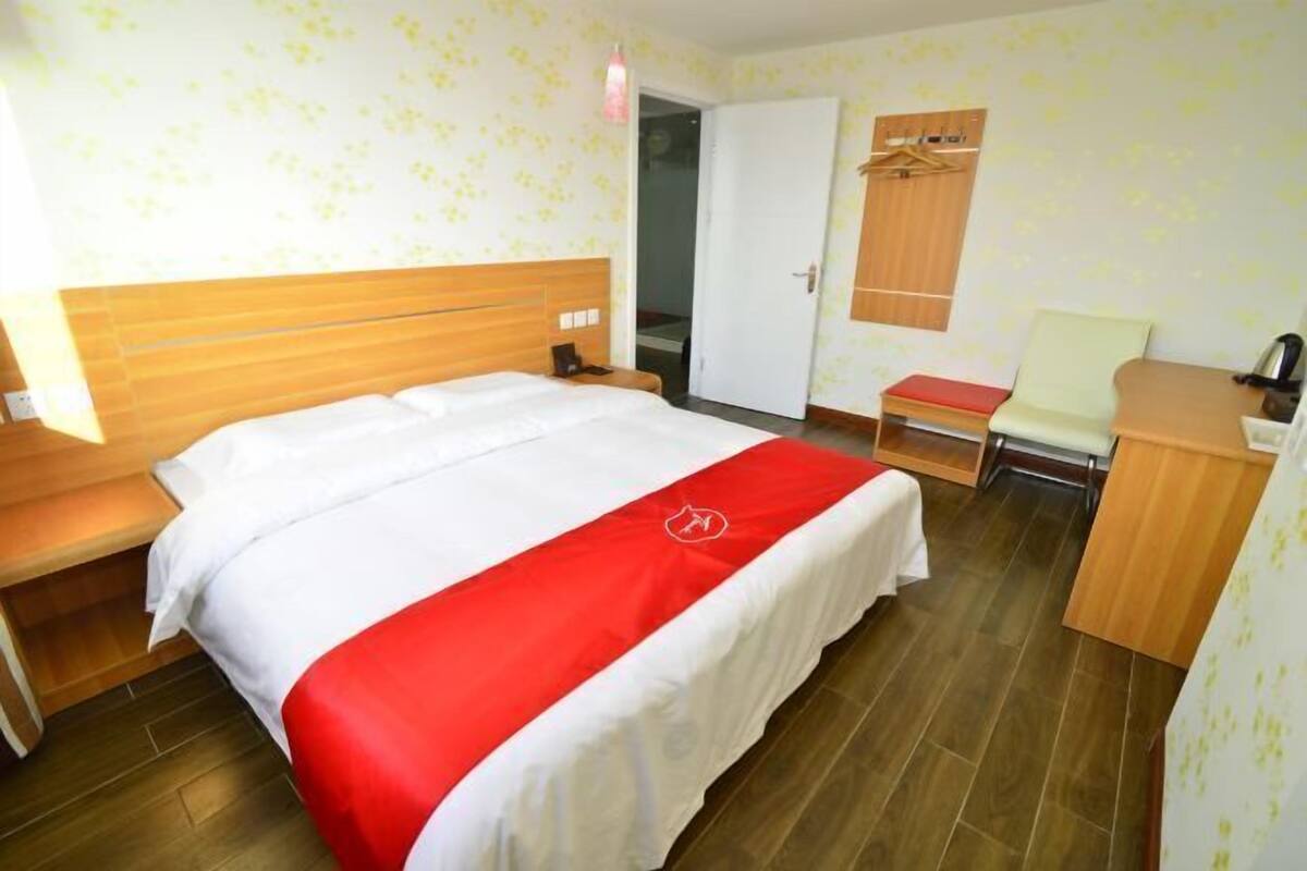 A hotel room with a bed, a desk, a chair, and a wardrobe.