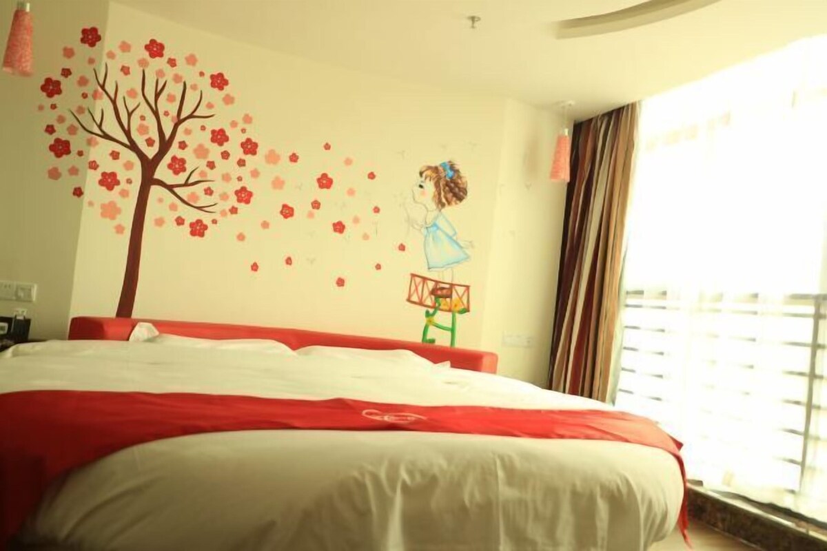 A hotel room with a bed, a wall mural, and a window with curtains.