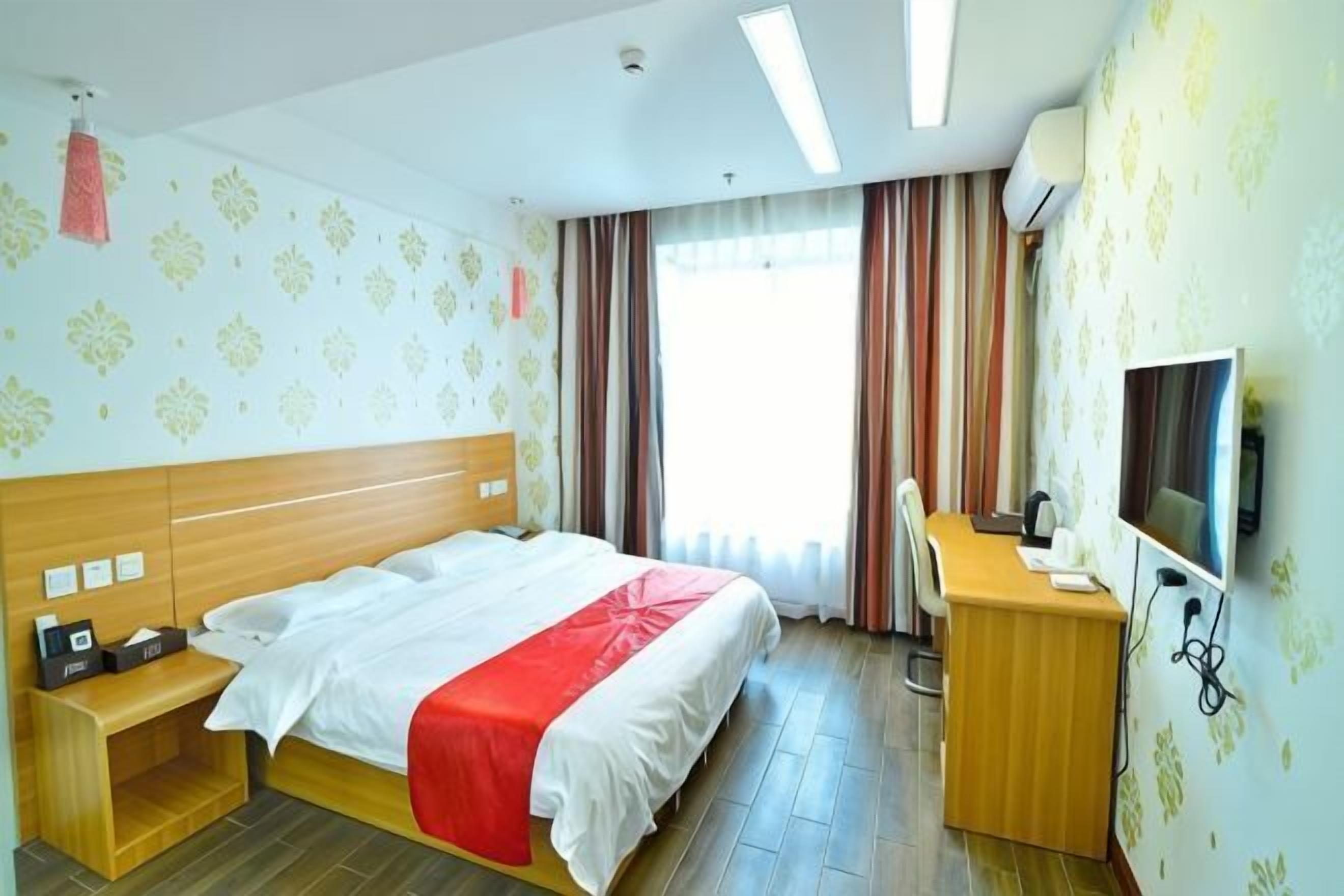Ein Hotelzimmer mit Bett, Schreibtisch und Fernseher.