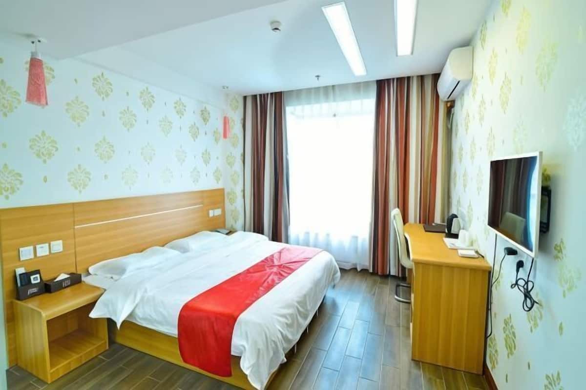 A hotel room with a bed, desk, and TV.