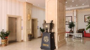 A lobby with a marble floor, a reception desk, a statue, and a red sofa. - Shankee Express Hotel (Meizhou Lijiangwan) (Meizhou)