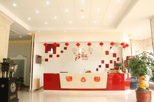 Zona de recepción de un hotel con una decoración en tonos rojo y blanco, un mostrador de recepción y farolillos decorativos rojos.