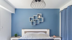 A modern bedroom with a bed, a geometric wall art piece, and a blue curtain. - Le Phenicia by Interhome (Saint Laurent du Var)