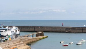Ein Hafen mit einer angedockten Fähre, einer Kaimauer und mehreren Booten.