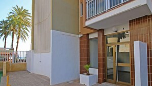 A modern building with a glass entrance, a small potted plant, and a balcony with a railing. - Voramar by Interhome (Calpe/Calp)