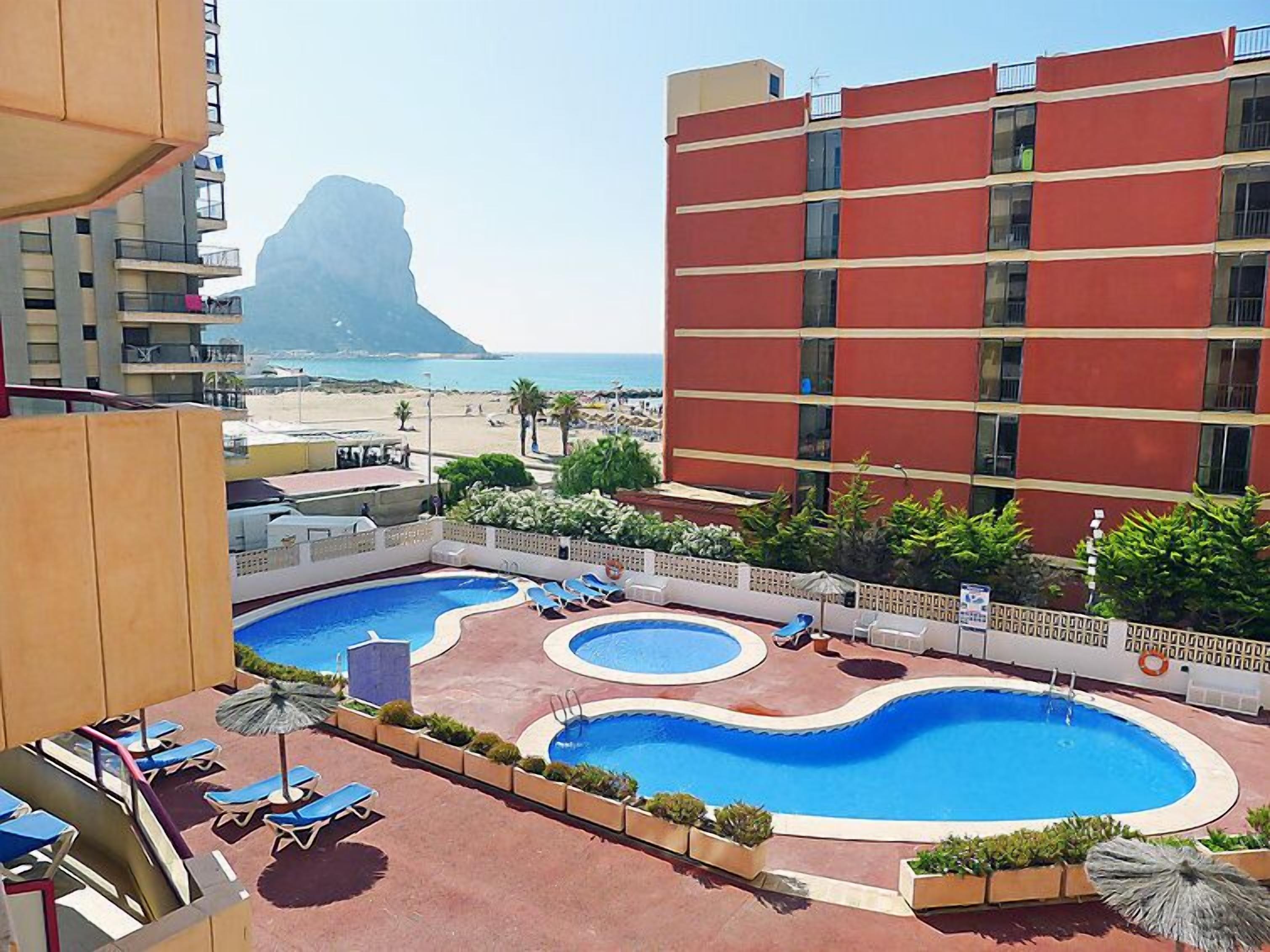 A hotel with a pool area, including multiple swimming pools and lounge chairs.