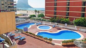 Ein Hotel mit Poolbereich, inklusive mehrerer Schwimmbecken und Liegestühlen.