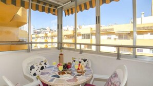 Ein Balkon mit Tisch für Zwei, Stühlen und Blick auf Gebäude im Hintergrund.