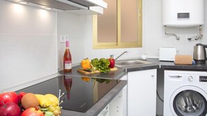 Une cuisine moderne équipée d’un lave-linge intégré, d’une cuisinière et d’une fenêtre avec des stores.