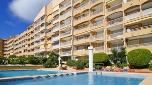 A multi-story hotel with balconies, a swimming pool, and landscaped greenery.