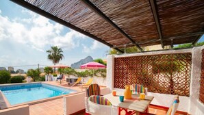 Ein Poolbereich mit gefliestem Boden, einem Pool und einem Tisch mit Stühlen.