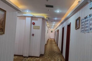 A hotel corridor with doors, a carpeted floor, and ceiling lights. - Yali Siji Business Hostel (Shenzhen)
