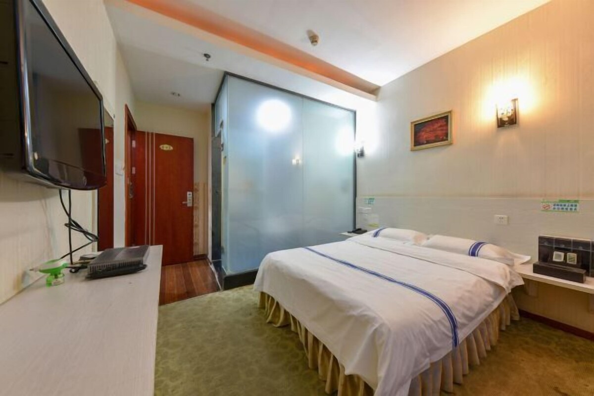 Ein Hotelzimmer mit Bett, Schreibtisch, Fernseher und Tür.